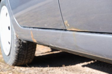 Paslı ve metal aşınmalı bir araba kapısı. Kaput arabasındaki paslı lekeyi yok et. Gümüş arabanın gövdesinde ve kapılarında sert aşınma ve pas var..