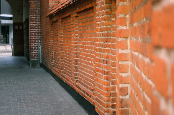 Kırmızı tuğla duvarlarla çevrili dar bir yol. Gündüz perspektifte iki kırmızı tuğla duvar arasında dar bir ara sokak.