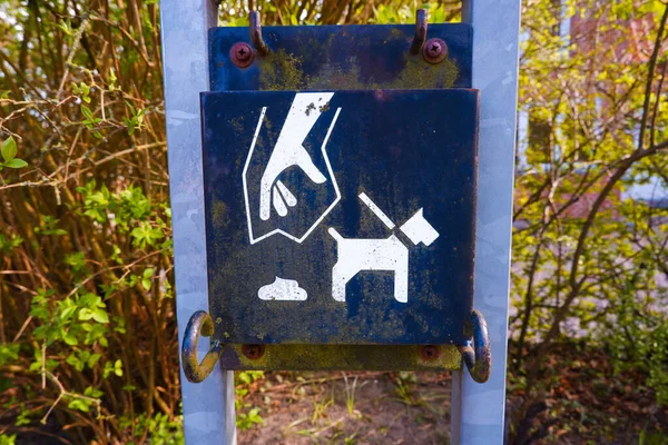 Dumpster for pet excrement in a public park. Cleaning dogs excrement on street. A sign and bin for pet waste in a park