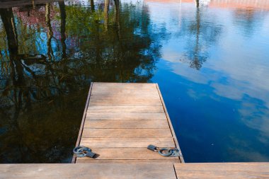 Manzara. Göldeki tekneler için ahşap set iskelesi. Şehir parkında yürümek için uygun bir yer. İskelesi ve güvertesi olan sıcacık su manzarası.