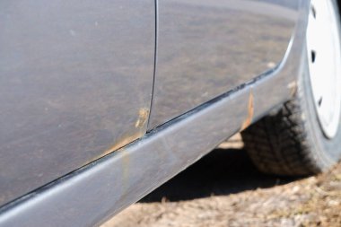 Paslı ve metal aşınmalı bir araba kapısı. Kaput arabasındaki paslı lekeyi yok et. Gümüş arabanın gövdesinde ve kapılarında sert aşınma ve pas var..
