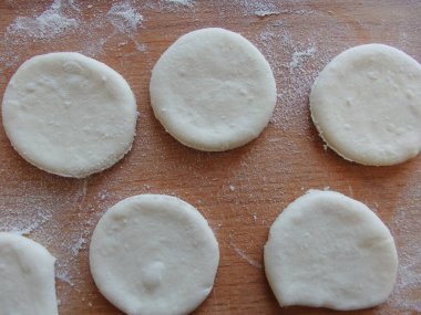 Maya hamuru pişiriyorum. Mutfakta hamurla çalışmak. Mangırları yakın plan çek. Çiğ hamur masada yuvarlandı. Yarı bitmiş ürünler yapmak.