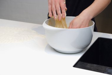 Ev yemeği konsepti. Genç bir kadın modern bir mutfakta hamur mayasıyla çalışıyor. Genç bir kadın hamur yoğuruyor, ev yapımı fırında çalışıyor..