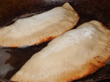 Yemek pişirmek. Chebureks pişiriyorum. Hamurda kızarmış et. Ulusal bir yemek. Cheburek, etli ve soğanlı kızarmış turta. Geleneksel Türk ve Moğol yemeği, börekler börek böreği