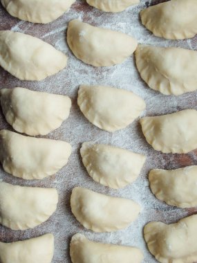 Yemek pişirmek. Süzme peynirli hamur tatlısı. Tahta üzerinde hazır hamur tatlısı. Çiğ hamur köfteleri, ahşap bir tahtanın üstünde pişirilmeye hazır, yakın çekim manzaralı..