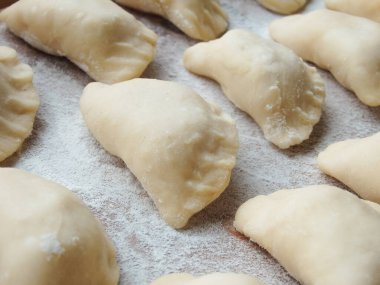 Yemek pişirmek. Süzme peynirli hamur tatlısı. Tahta üzerinde hazır hamur tatlısı. Çiğ hamur köfteleri, ahşap bir tahtanın üstünde pişirilmeye hazır, yakın çekim manzaralı..