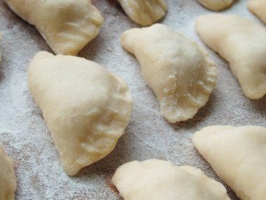 Yemek pişirmek. Süzme peynirli hamur tatlısı. Tahta üzerinde hazır hamur tatlısı. Çiğ hamur köfteleri, ahşap bir tahtanın üstünde pişirilmeye hazır, yakın çekim manzaralı..