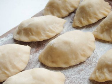 Yemek pişirmek. Süzme peynirli hamur tatlısı. Tahta üzerinde hazır hamur tatlısı. Çiğ hamur köfteleri, ahşap bir tahtanın üstünde pişirilmeye hazır, yakın çekim manzaralı..