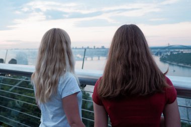 Gözlem masasındaki iki genç kız Kiev, Ukrayna 'nın merkezindeki Dinyeper nehrine bakıyor, hava manzaralı. Arkadan bak. Dişiler şehre bakıyor..