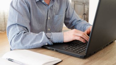 Evden çalışan bir iş adamı. Freelancer ofisteki bir dizüstü bilgisayarda çalışıyor. Adam masada oturuyor ve dizüstü bilgisayar kullanıyor.