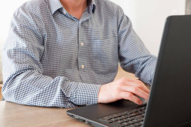 Evden çalışan bir iş adamı. Freelancer ofisteki bir dizüstü bilgisayarda çalışıyor. Adam masada oturuyor ve dizüstü bilgisayar kullanıyor.