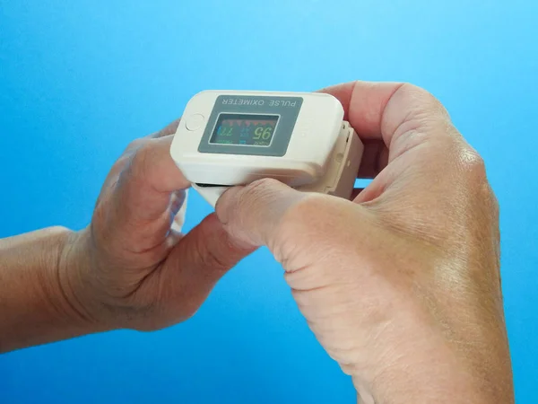 Woman Using Fingertip Pulse Oximeter Blue Background Top View — Stockfoto