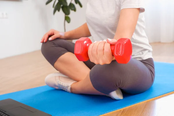 Home workout with laptop and work at home concept. Fitness woman watching online lesson at laptop and exercising with a fitness rubber band indoors. caucasian sporty woman having online fitness class at home.