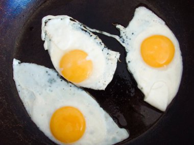 Tavada zeytinyağıyla kızartılmış 3 yumurta. Tavada üç yumurtalı sahanda yumurta. Siyah arkaplan