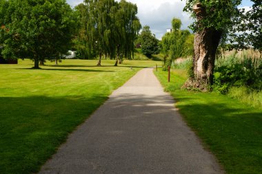 Empty gravel walk path with fresh green trees at day time for background with copy space. lawn, gravel path and trees in the park