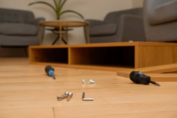 Assembly of furniture, the different parts and pieces of furniture arranged on the wooden floor. DIY furniture assembly concept. screwdriver and a lot of bolts and screws