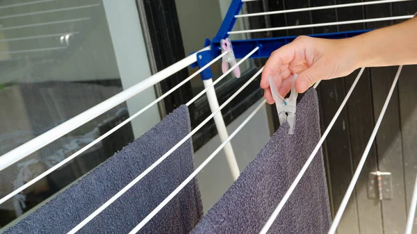 Woman hands hanging her laundry on balcony on the drying rack. Female Hanging Clothes On Clothes Line Outdoors. housewives drying clothes on the balcony of a condo or apartment