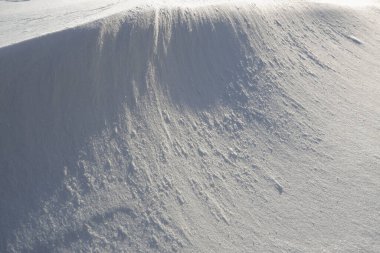 Abstract snow texture background. Close up snow dunes lines. Snowdrift, dune.