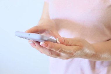 Woman hand using smartphone on light background. Woman using a Phone, close up, side view. Girl With Mobile Smart Phone