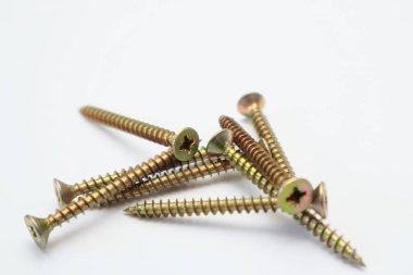 A bunch of yellow screws on a white background. yellow construction screws on white, side view, copy space. Heap of yellow screwson a white background.
