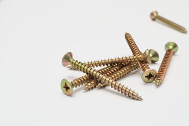 A bunch of yellow screws on a white background. yellow construction screws on white, side view, copy space. Heap of yellow screwson a white background.