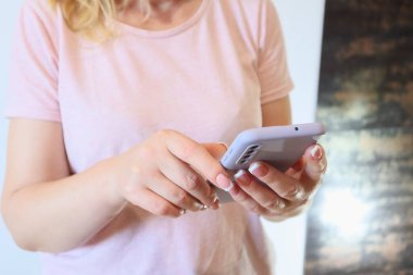 Hands using a Smartphone. Midsection Of Woman Using Mobile Phone At Home. Cropped anonymous female using mobile phone.