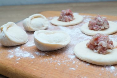 Dumplings with meat. The process of cooking Asian gyoza dumplings. Flour, dough on a wodden background. Home cooking dumplings, dough and minced meat