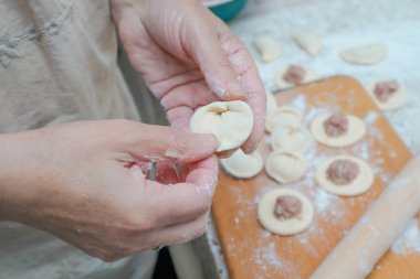 Raw homemade dumpling with meat in hands of housewife. Making process of convenience food. Raw dough