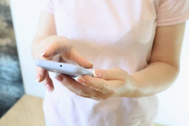 Woman hand using smartphone on light background. Woman using a Phone, close up view. Close up woman use of smart phone