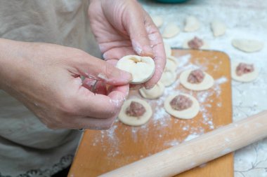 Raw homemade dumpling with meat in hands of housewife. Making process of convenience food. Raw dough