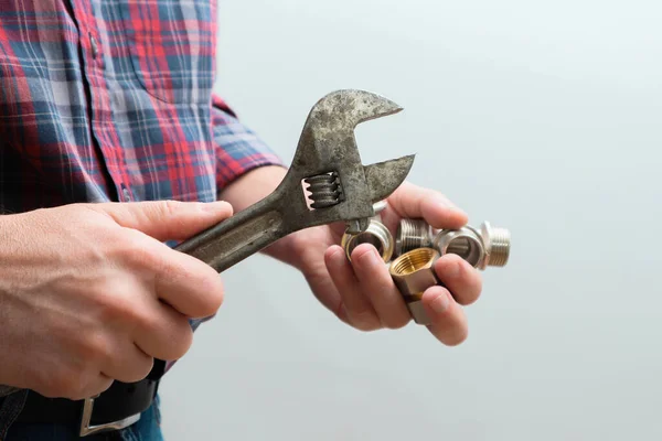 Plumbing services, plumber at work. Close-up of plumber hands with wrench over plumbing tools background. Concept of repair and technical assistance.