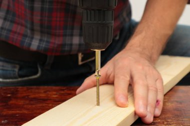 Handworker working with an electric screwdriver. A man using the drill in the home