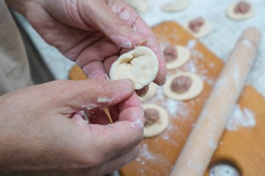 Raw homemade dumpling with meat in hands of housewife. Making process of convenience food. Raw dough