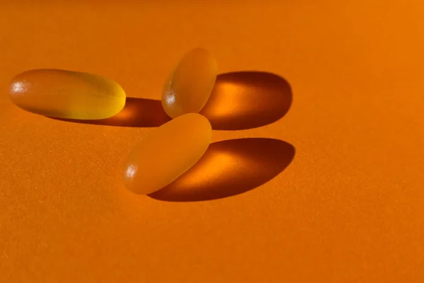 Dietary supplementation. omega-3 fish fat oil capsules. Orange background. Omega-3 vitamins, fatty acids.