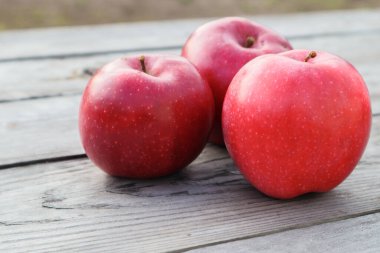 Kırsal gri tahta bir tahtanın üzerinde olgun kırmızı elmalar. Elmalar arka plandaki gri masaya yakın plan. Boşluğu kopyala
