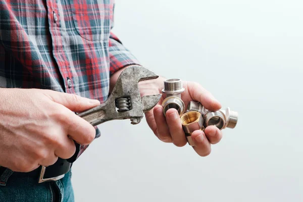 Plumbing services, plumber at work. Close-up of plumber hands with wrench over plumbing tools background. Concept of repair and technical assistance.