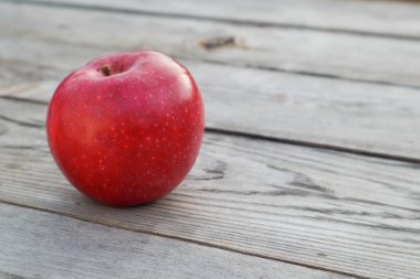 Kırsal gri tahta üzerinde olgun kırmızı bir elma. Apple, gri bir masanın üzerinde, arka plandaki tahtalara karşı yakın plan. Boşluğu kopyala