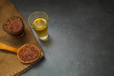 Kaşık üzerinde kahverengi keten tohumu, keten tohumu yağı. Kasede keten tohumu, camda keten tohumu yağı gri taşlı arka planda, yakın plan, seçici odak