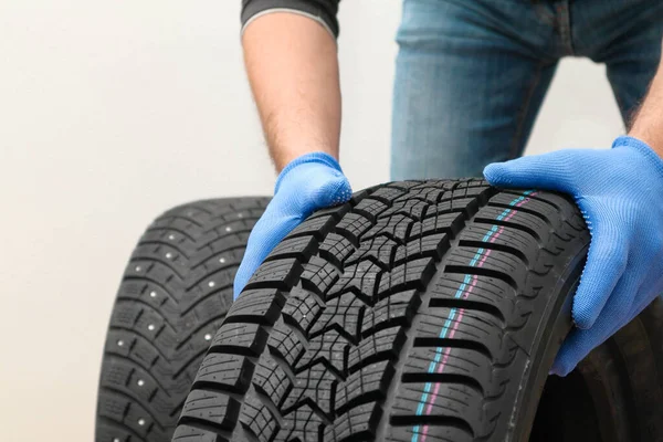 Mechanic holding a tire at the repair garage. Replacement of winter and summer tires. winter studded tyre, tires replacement