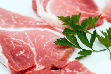 Beyaz maydanozlu çiğ pastırma dilimleri. Beyaz tabakta taze çiğ domuz eti.