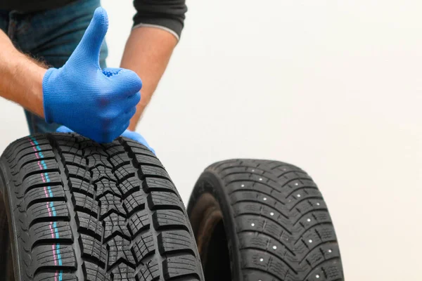 Mechanic holding a tire at the repair garage. Replacement of winter and summer tires. winter studded tyre, tires replacement