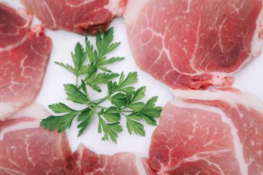 Beyaz maydanozlu çiğ pastırma dilimleri. Beyaz tabakta taze çiğ domuz eti.