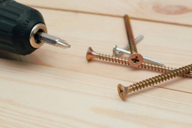 Aletli masa. Tahta bir masada elektrikli tornavida. Siyah metalik vidaların yan görünümü, Wodden tahtalarında elektrikli tornavida.