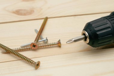 Aletli masa. Tahta bir masada elektrikli tornavida. Siyah metalik vidaların yan görünümü, Wodden tahtalarında elektrikli tornavida.