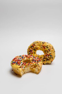 Beyaz arka planda ısırılmış renkli çöreklerle donutlu pasta.