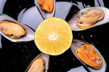 Bir dilim limon ve dereotlu siyah tabakta midye.