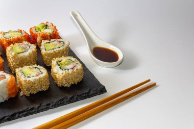 Suşi tepsisi beyaz arka planda soya sosu ve yemek çubuklarıyla kaplı. Uzayı kopyala Seçici odak.