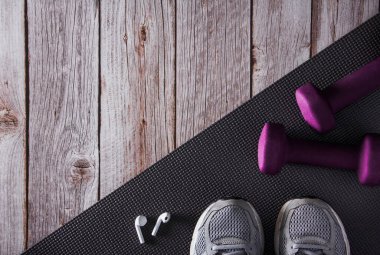 Fitness halterleri, spor ayakkabıları ve kulaklıklar mindere. Jimnastik aksesuarları. Uzayı kopyala Seçici odak.