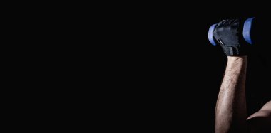 Genç adam dambıllarla kas ve güç egzersizleri yapıyor. Yüksek yoğunluklu fitness. Uzayı kopyala Seçici odak.