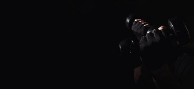 Genç adam dambıllarla kas ve güç egzersizleri yapıyor. Yüksek yoğunluklu fitness. Uzayı kopyala Seçici odak.